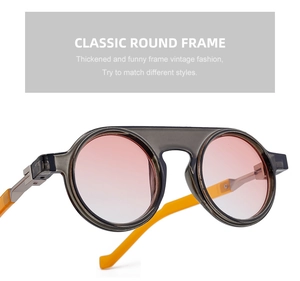Detail of round sunglasses with grey translucent frames and pink gradient lenses