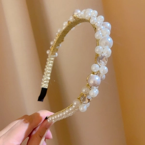 Close-up of golden headband featuring sparkling rhinestones and white pearls detail