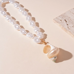 Detailed view of baroque pearl necklace featuring a natural conch shell and gold metal clasp