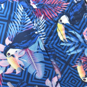 Detailed macro view of reversible sun hat fabric with tropical toucan and palm leaf patterns