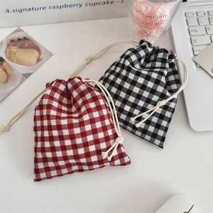 Detail view of red and black checkered drawstring pouches on a minimalist workspace