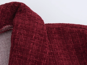 Makro-Detail der roten Tweed-Stoffstruktur am V-Ausschnitt und der Schulter des Kleides