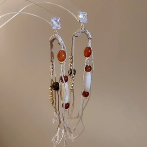 Macro shot of bohemian tassel earrings with square crystal and woven ethnic details