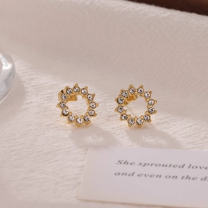 Élégantes boucles d'oreilles rondes dorées avec cristaux de zircon sur tissu blanc