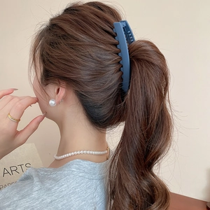 Détail d'une pince banane en acrylique bleu mat portée avec des boucles d'oreilles