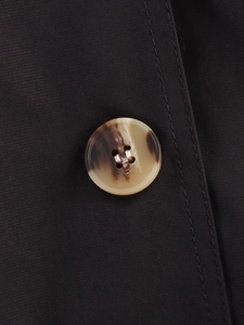 Detailed close-up of a tortoiseshell resin button on a black trench coat fabric