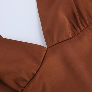 Vue détaillée du décolleté en V et des plis drapés sur ce haut licou en satin marron
