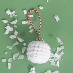 Close-up of a white knitted Christmas ball ornament with a red and white twisted cord