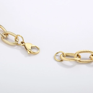 Macro detail of golden twist chain necklace with lobster clasp and threaded texture