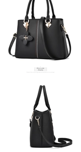 Side view of a black PU leather handbag with beaded lines and a gold floral charm