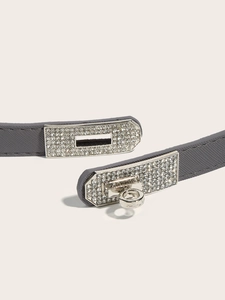 Detail of grey leather belt featuring a silver lock buckle with sparkling rhinestones
