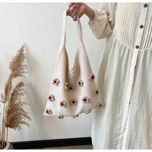 Detailed close-up of a white knitted tote bag featuring 3D brown floral accents