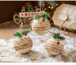 Close-up of linen Christmas balls with pine needles and red berries on a snowy wooden table