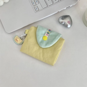 Gros plan d'un joli porte-cartes jaune pour étudiants avec un petit charme d'ours