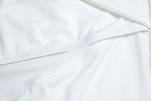 Detail shot of the white dress featuring high-quality stitching and elastic fabric texture