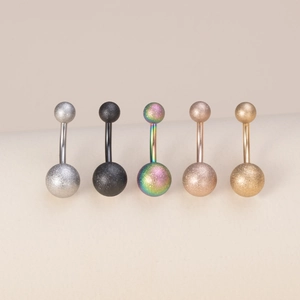 Detail shot of five matte finish curved barbell belly button rings in various metallic colors