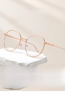 Detail of rose gold metal frame glasses with embossed textures on cream stone