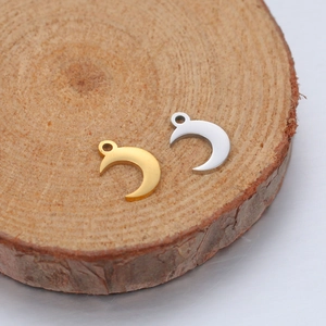 Close-up of gold and silver moon shaped stainless steel pendants on a wooden base