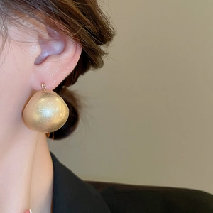 Close-up of minimalist matte gold U-shaped basket earrings on a model with side view