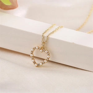 Macro shot of gold heart pendant with white pearls and sparkling zircons on silk