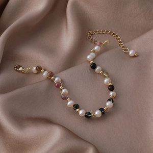 Detailed macro of irregular baroque pearls and colored gemstones on a silk fabric background