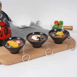 Three styles of miniature simulation buckwheat noodle bowl keychains on a wooden tray