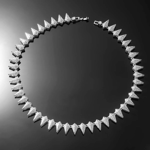Macro detail of iced-out silver necklace featuring triangular links with cubic zirconia stones