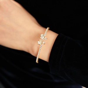 Vue macro d'un bracelet papillon doré avec zircon violet sur fond de velours noir