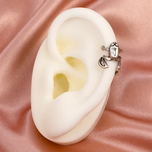 Macro shot of silver frog ear cuff on model with a smooth pink satin background