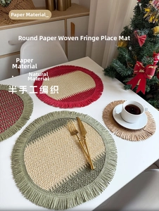 Detailed view of woven paper Christmas placemat with red green fringe and festive cutlery