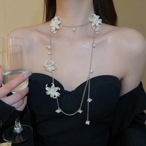 Detailed view of multilayer pearl and acrylic flower necklace with silver chain on a model