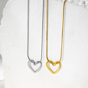 Macro detail of hollow heart pendants in gold and silver finish with snake chains