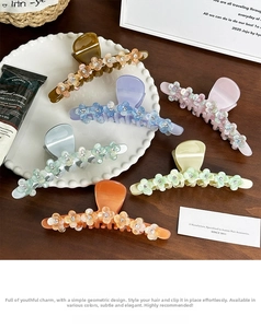 Detail showing various colors of acetate flower hair claws with rhinestones on a plate