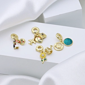 Gold-plated enamel charms featuring wedding, travel, and nature themes on satin display