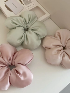 Detailed texture of satin flower hair scrunchies in mint green and pastel pink tones