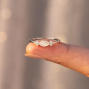Close-up of marquise-cut opal ring with zircon accents on finger for women