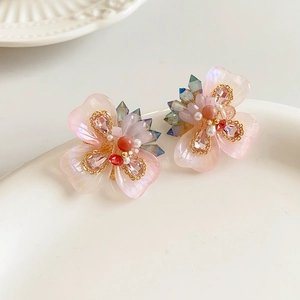 Vue détaillée de boucles d'oreilles fleurs avec pétales en résine rose et perles