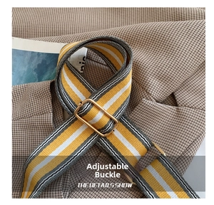 Detail of adjustable bag strap with yellow grey stripes and golden metal buckle