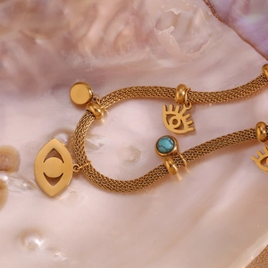 Macro detail of 18K gold mesh chain bracelet with evil eye charms and turquoise bead