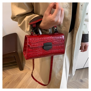 Detail of red crocodile texture glossy leather bag with matte black metal lock buckle