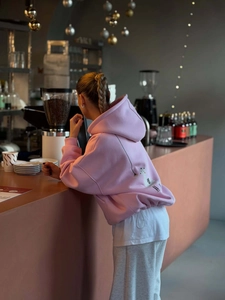 Pink oversized hoodie for women featuring a cute back cat print in a cozy cafe setting