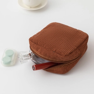 Detailed macro shot of brown corduroy makeup bag with zipper and cosmetic items