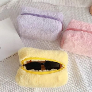 Three plush macaron-colored makeup bags in purple, pink, and yellow with top zipper closure