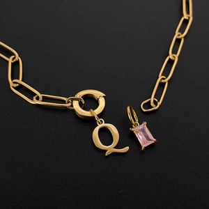 Detailansicht von vergoldetem Anhänger Buchstabe Q und rosa Edelstein an Gliederkette.