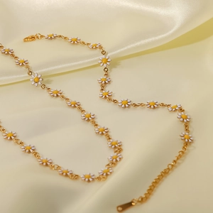 Detalle del collar de margaritas en oro de 18K con flores blancas sobre seda beige