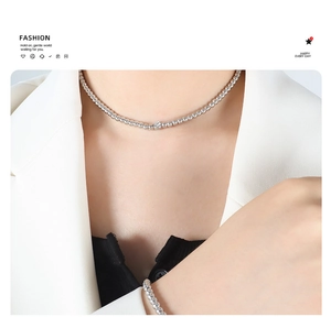 Polished silver beaded necklace and bracelet set displayed on a model in a minimal suit
