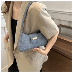 Detail of gray felt baguette bag showing soft texture and gold rectangle metal clasp