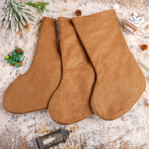 Trois chaussettes de Noël brunes sur la neige avec lanterne et sapins