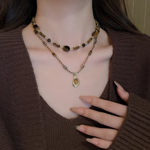 Détail d'un collier double épaisseur vintage avec perles d'ambre et pendentif doré