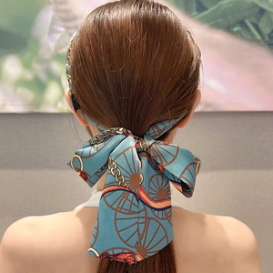 Detail of a patterned blue and orange ribbon headband styled in a bow for women
